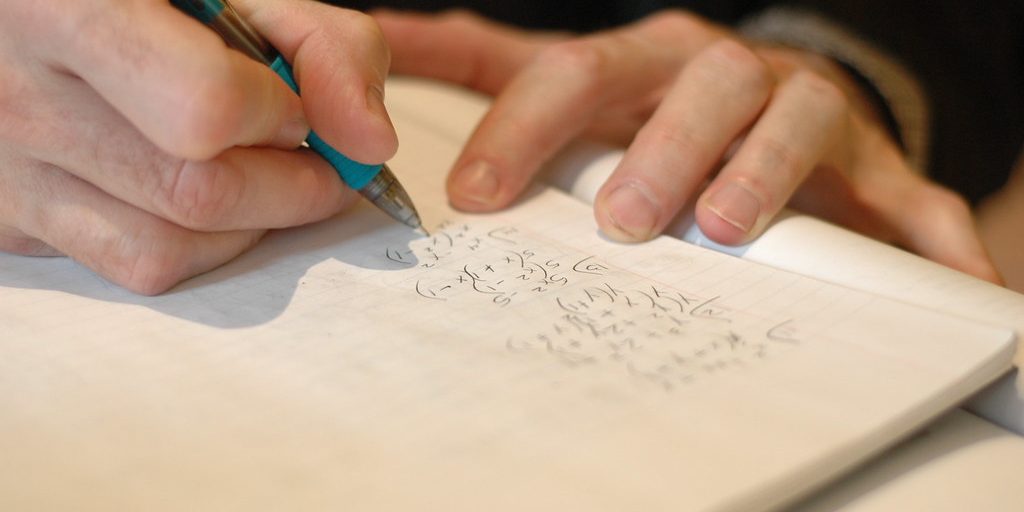 A hand writing notes in a lined notebook